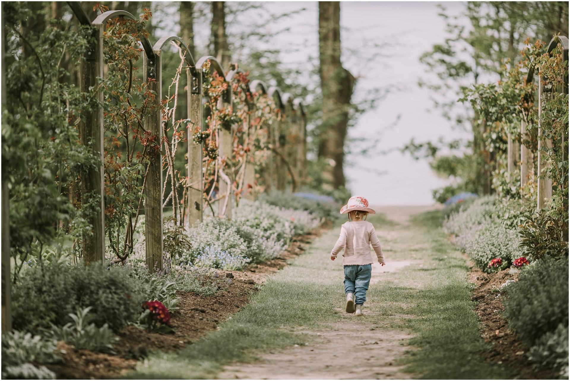 Charlotte Kiri Photography - Family Photography of a young girl who is wearing a sunhat and walking amongst the vines in Wanaka, New Zealand.