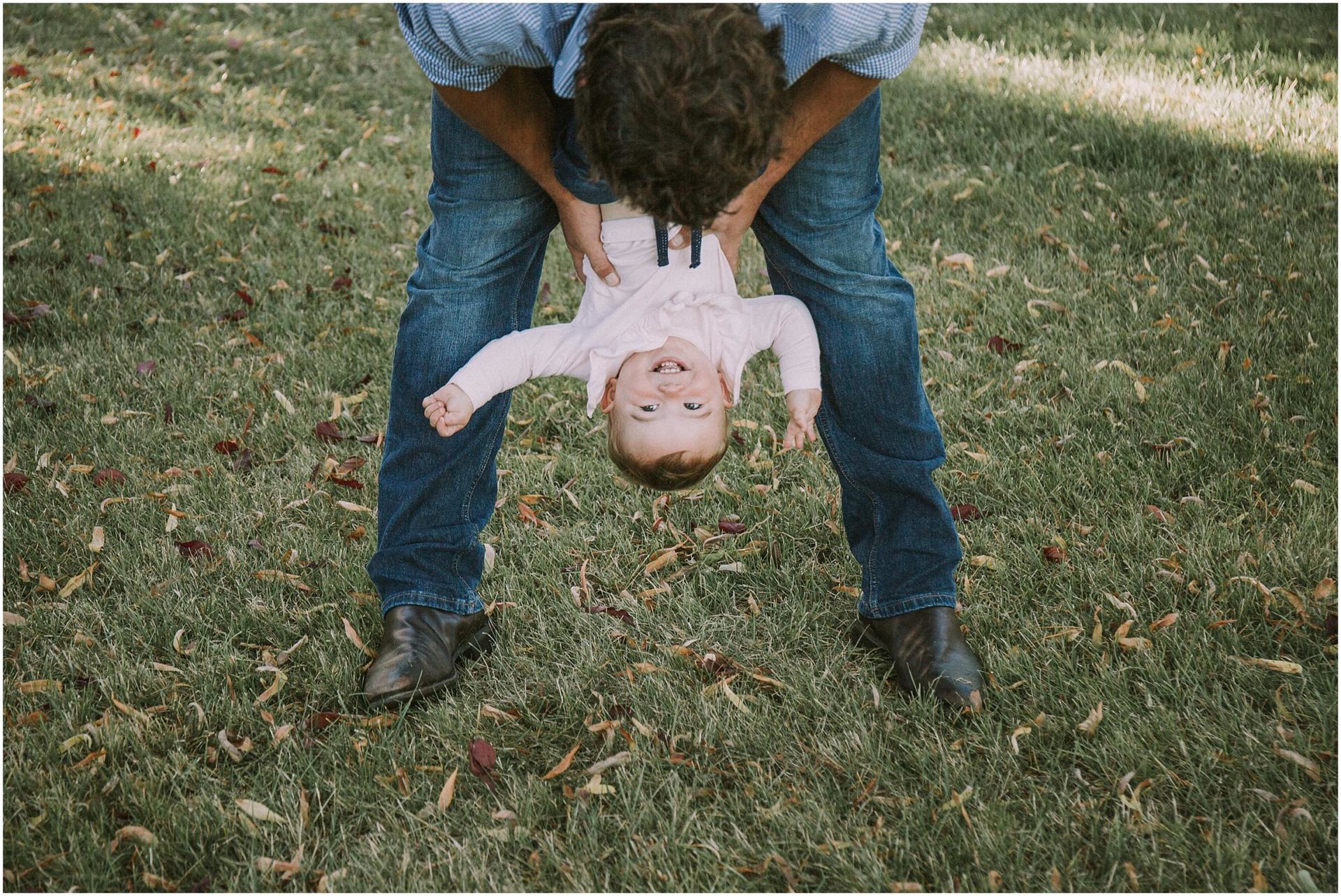 Charlotte Kiri Photography - Family Photography of a father dipping his child upside down playfully in a garden in Wanaka, New Zealand.