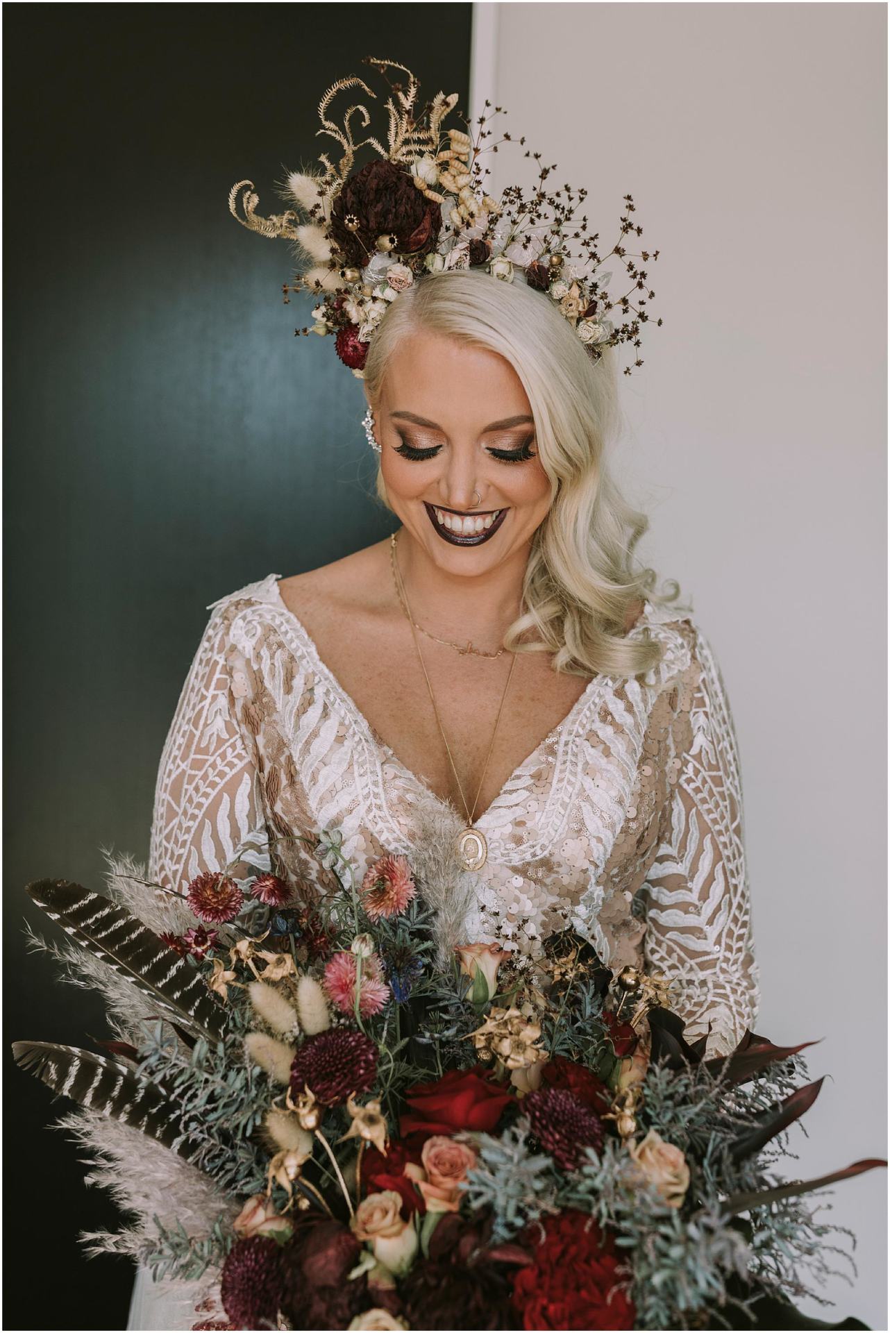 Charlotte Kiri Photography - Wedding Photography with a striking bride wearing a low V-necked dress with champagne-lined lace and holding a rustic bunch of roses and feathers and toi toi, with a stunning floral tiara with sculpted foliage