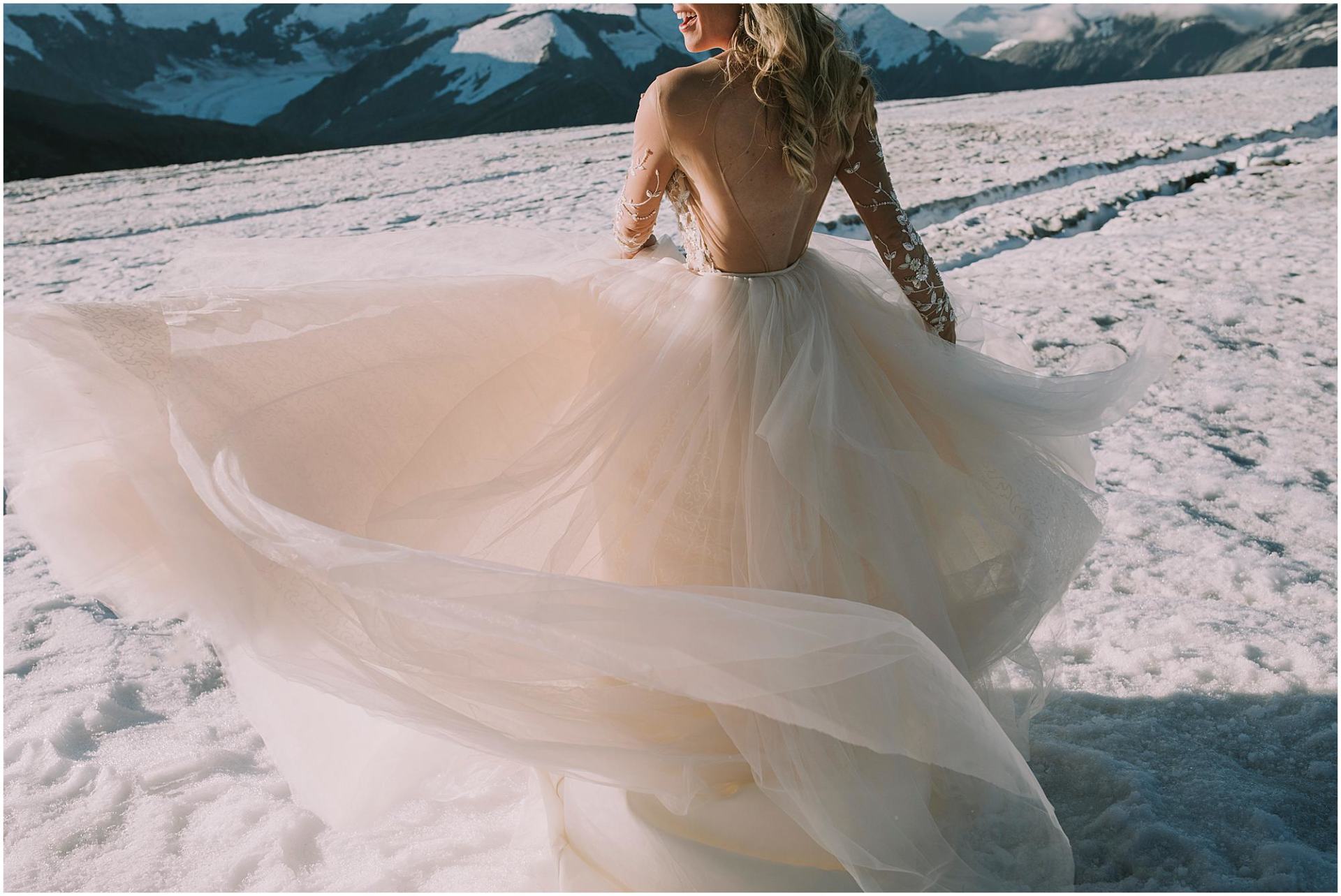 Charlotte Kiri - Wedding Photography of a bride spinning her beautiful champagne tulle skirt as she dances on a frozen glacier in Wanaka, New Zealand
