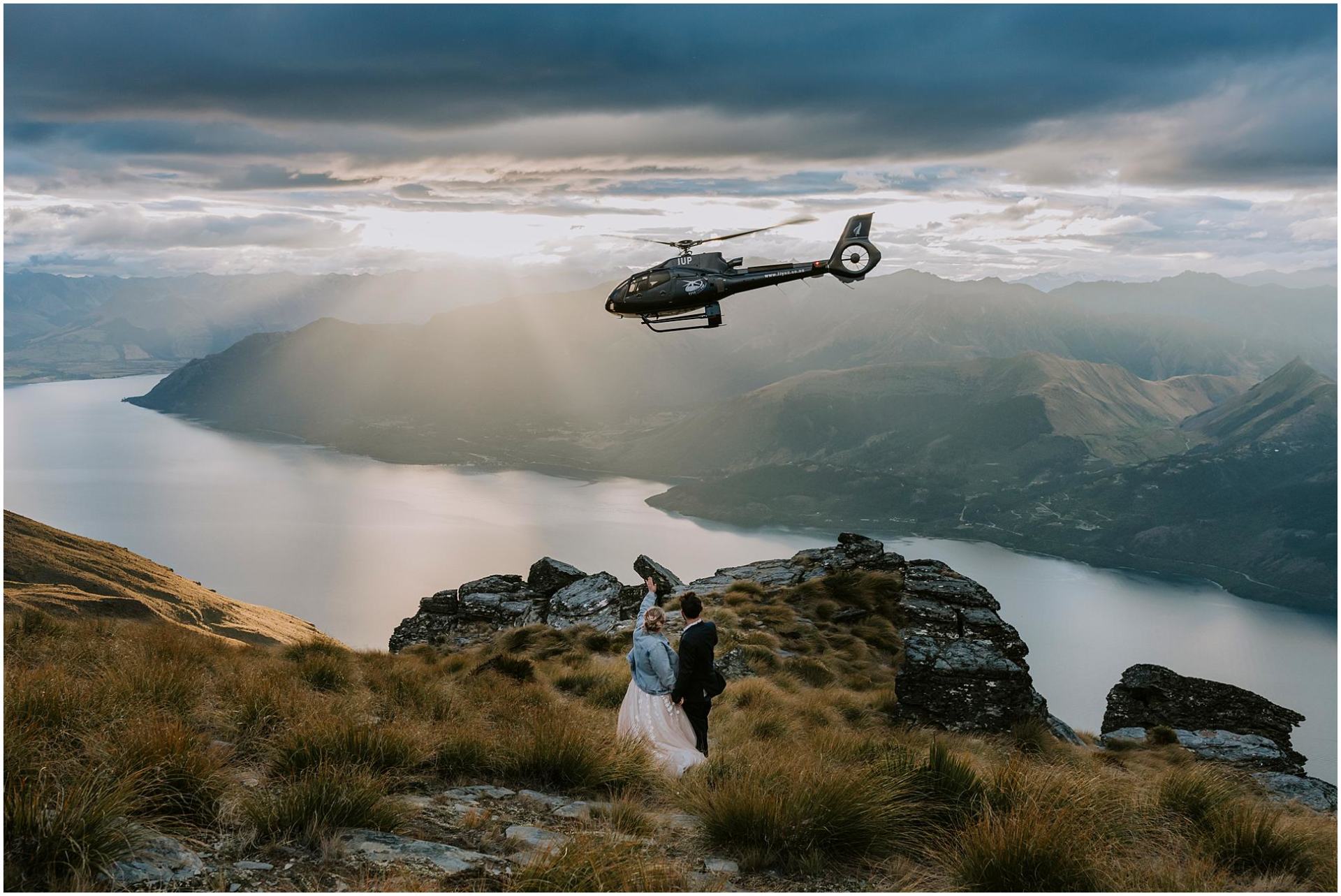 Charlotte Kiri Photography - elopement photography couple waving farewell to helicopter standing on top of Coromandel Peak Wanaka Queenstown New Zealand