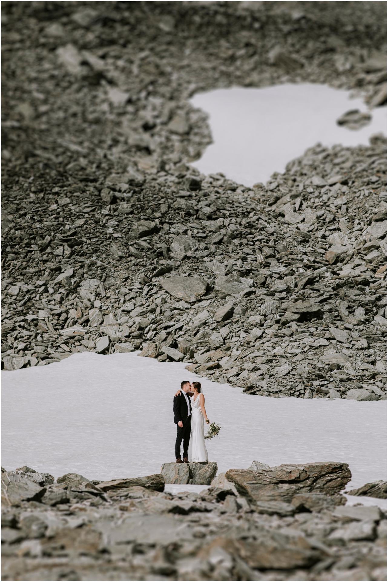 Charlotte Kiri Photography - Wedding Photography with a bride and groom kissing on the edge of a glacier on Coromandel Peak in Wanaka, New Zealand.