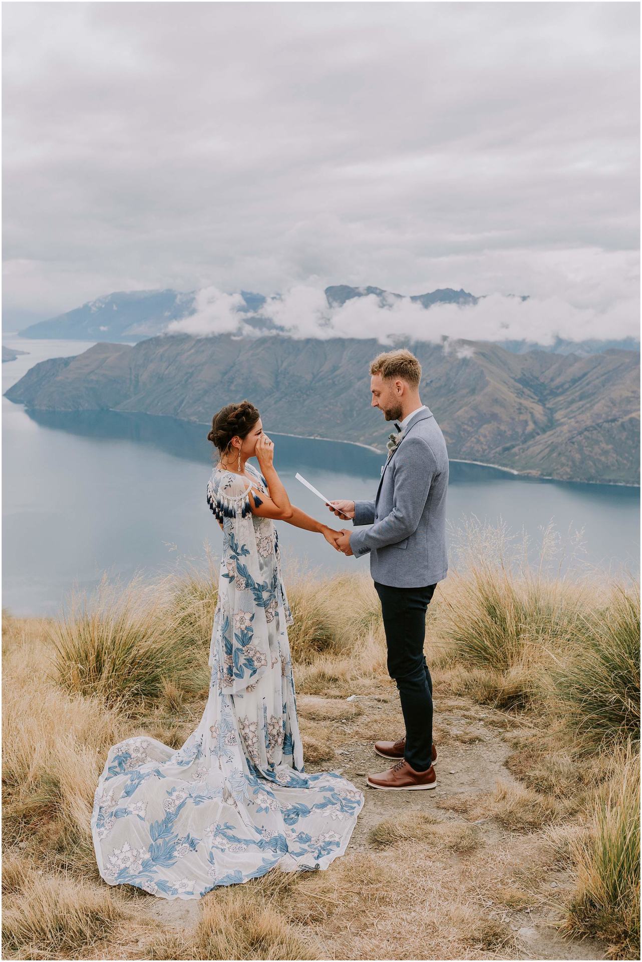 Charlotte Kiri Photography - elopement photography with the groom reading vows to his emotional bride on top of Roy's Peak, which overlooks a beautiful lake and mountain view in Wanaka, New Zealand