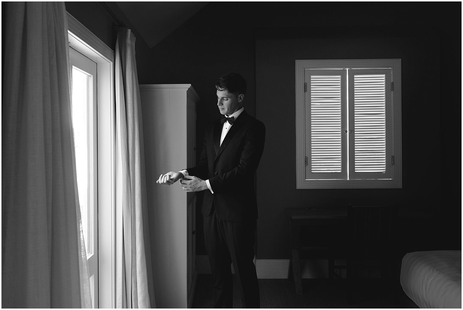Charlotte Kiri Photography - Wedding Photography of a groom doing up his cufflinks as he stands in front of the window of his hotel room before the wedding in Wanaka, New Zealand.